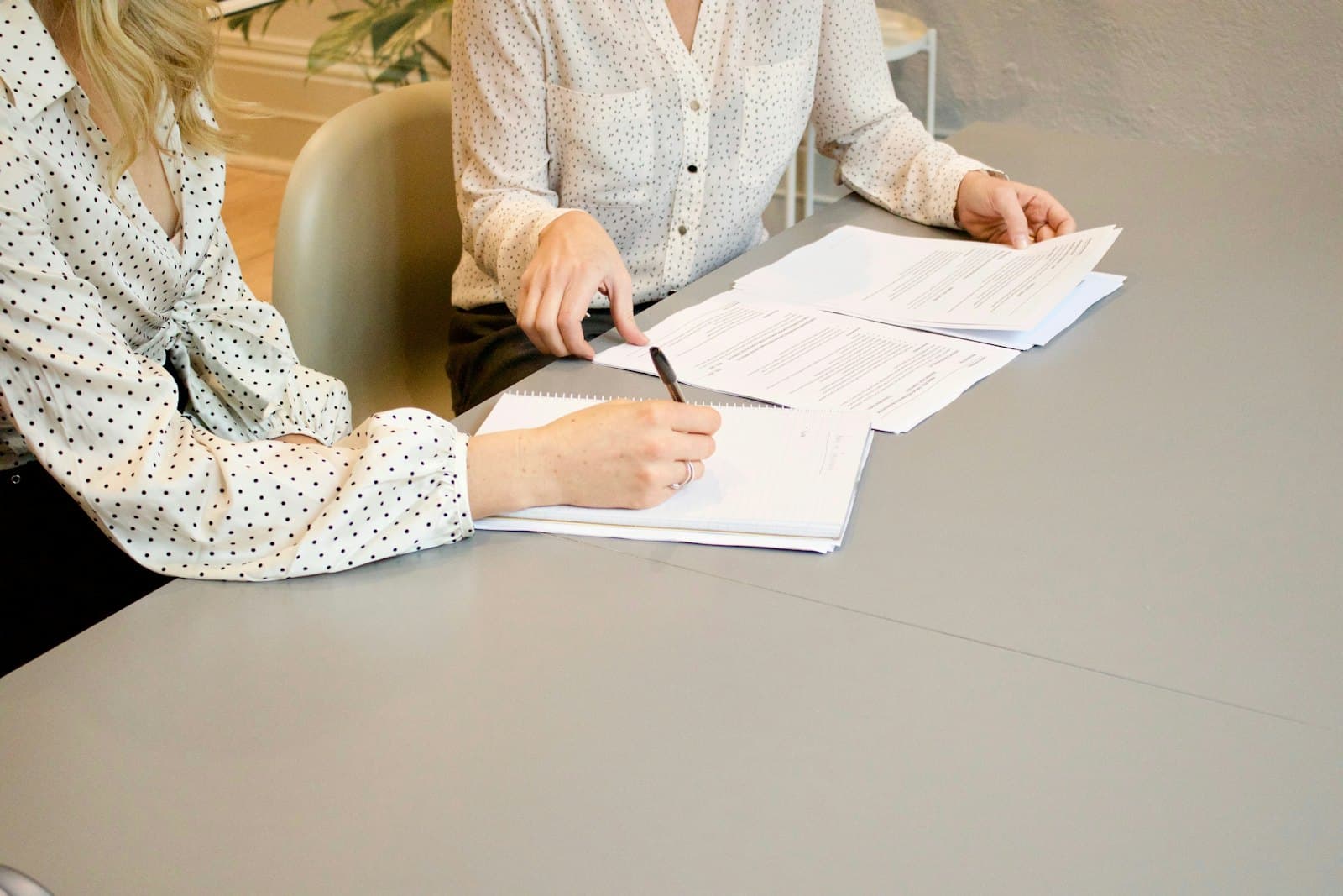 Deux personnes relisent un contrat et prennent des notes.
