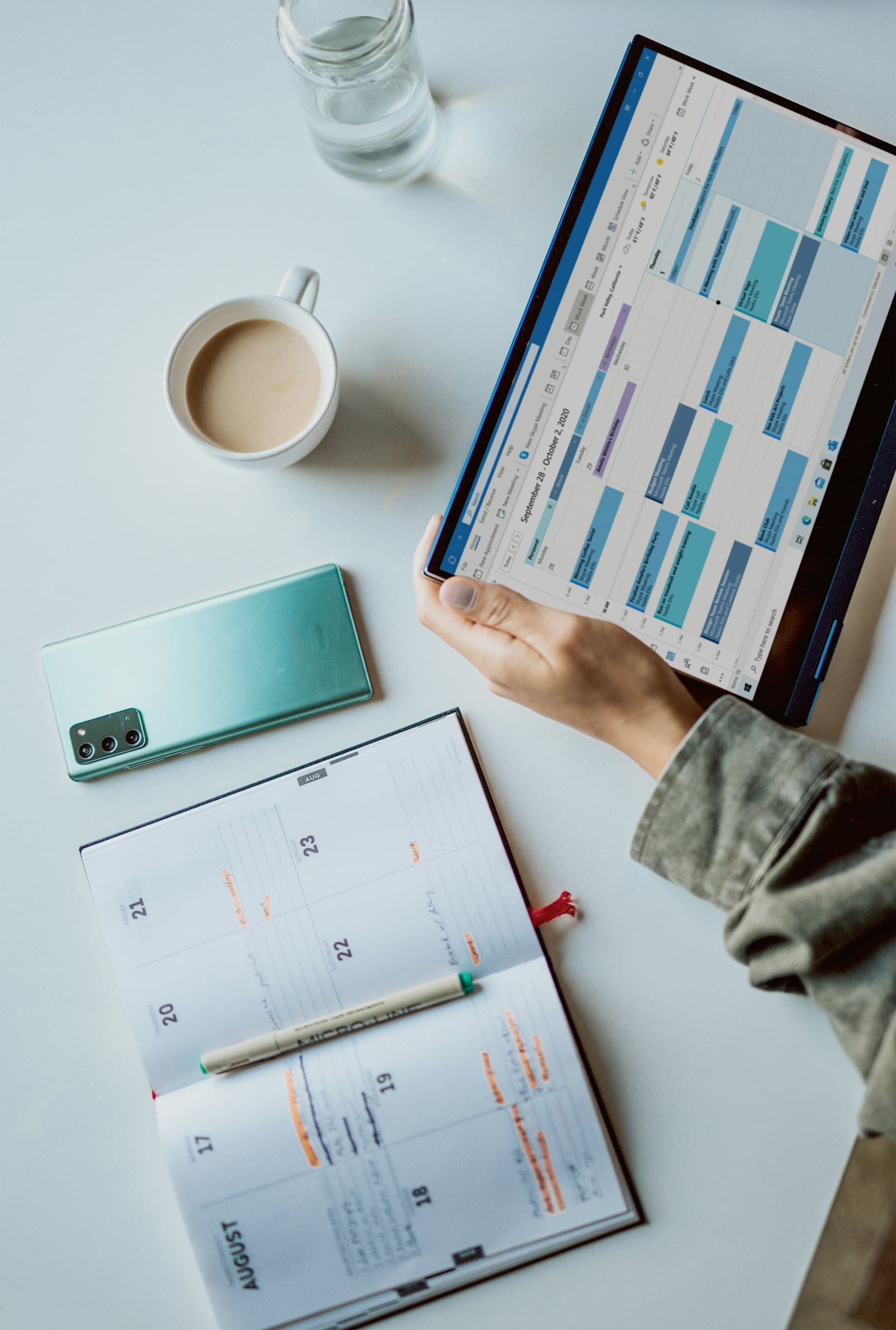 Un cahier de rendez-vous en papier ouvert à côté d'un agenda numérique affiché sur une tablette.