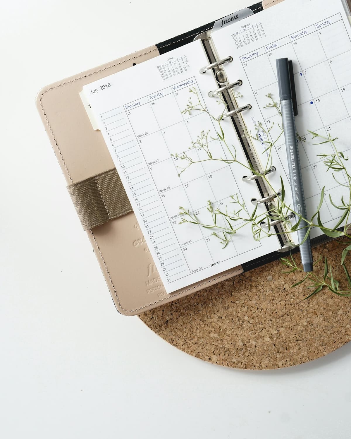 Un cahier de rendez-vous en papier, ouvert, avec son stylo.